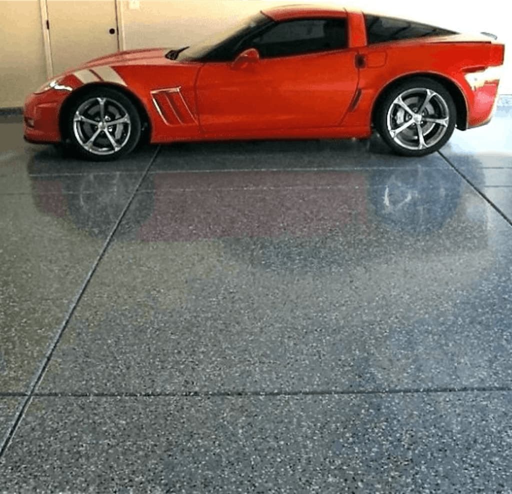 Bright red sports car parked on a glossy flake epoxy garage floor